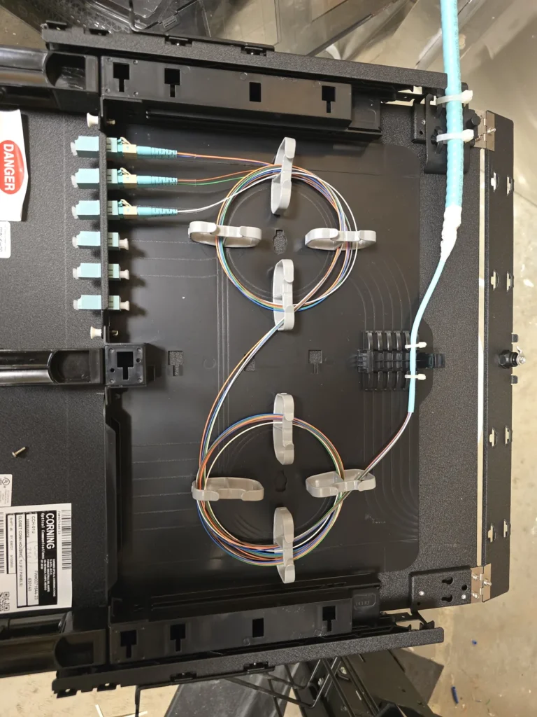 Fiber optic enclosure with organized strands and aqua fiber connectors.