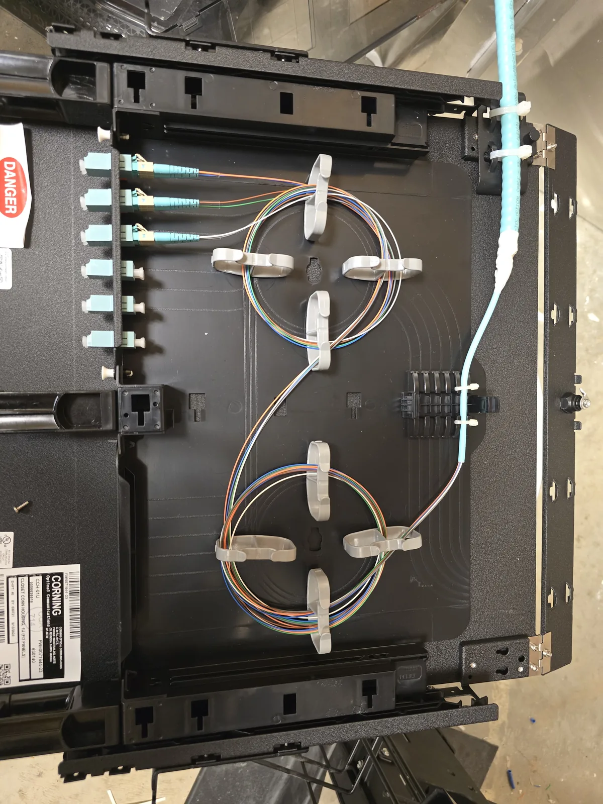 Fiber optic enclosure with organized strands and aqua fiber connectors.